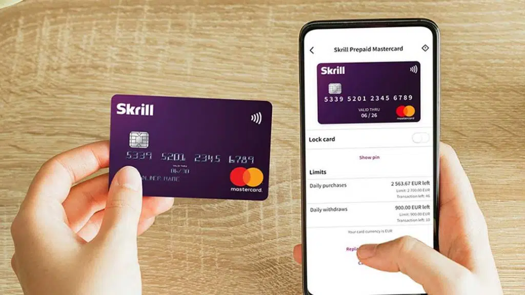 Skrill prepaid Mastercard held beside a smartphone displaying the Skrill app